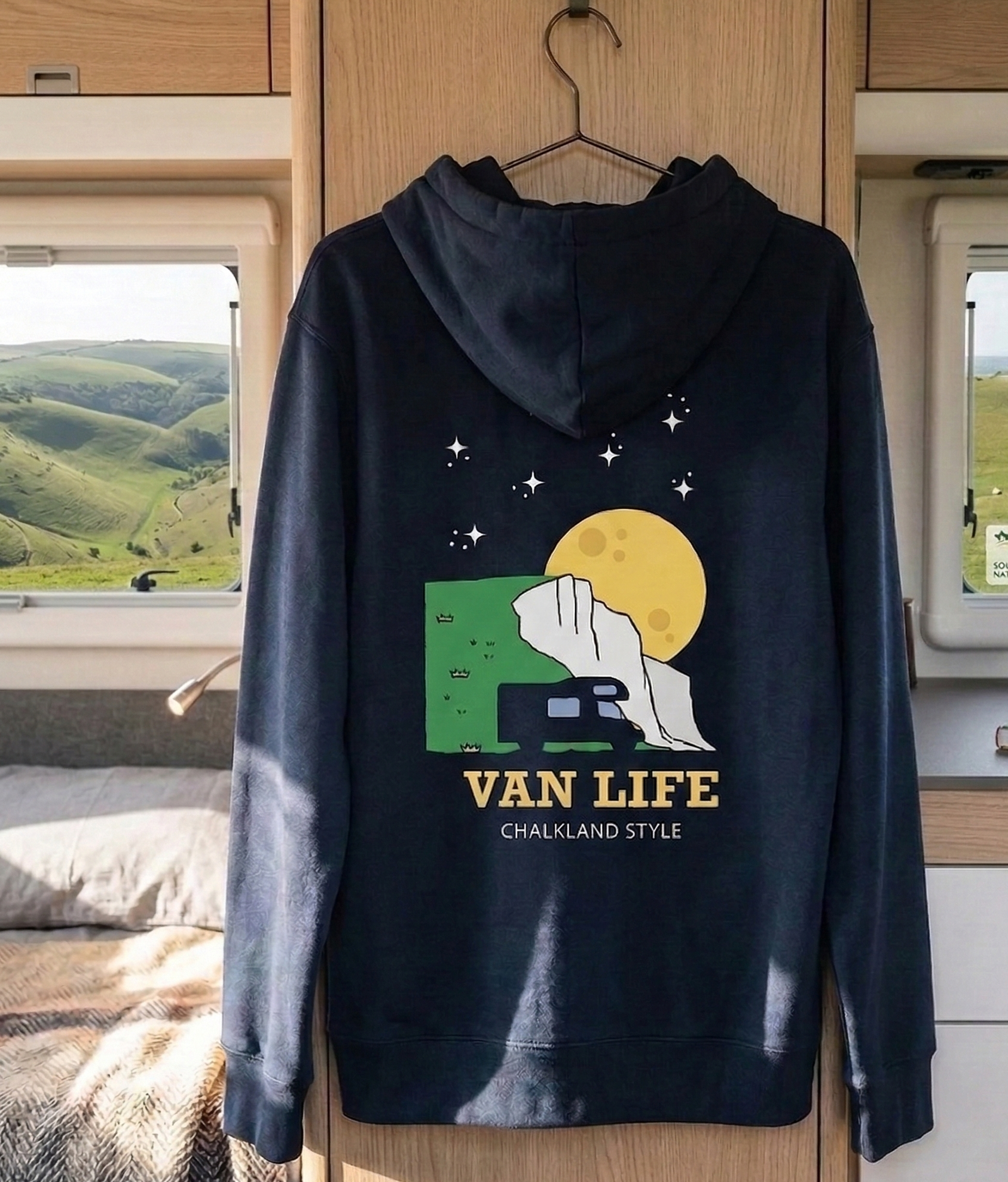 Navy blue hoodie with 'Van Life' graphic design hanging in a vehicle interior.